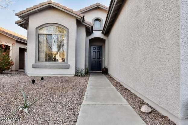 property entrance featuring stucco siding and a tile roof