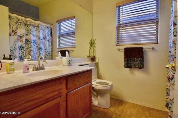 bathroom with tile patterned floors, a healthy amount of sunlight, toilet, and vanity