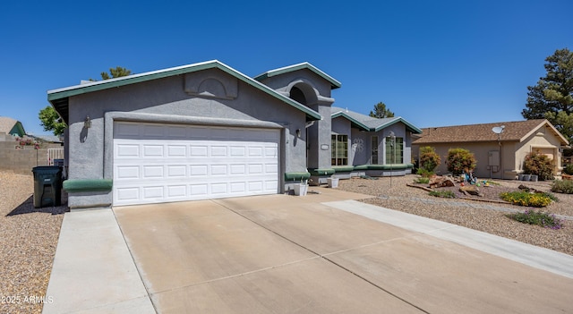 ranch-style house with concrete driveway, an attached garage, and stucco siding