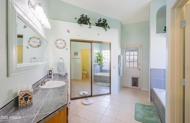 full bath with vanity, tile patterned flooring, a garden tub, and toilet
