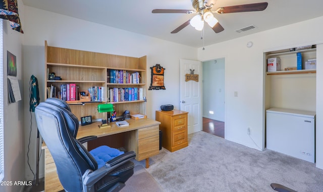 office area with a ceiling fan, visible vents, and light carpet