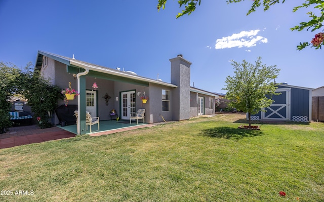 rear view of house featuring a storage unit, stucco siding, an outbuilding, a patio area, and french doors