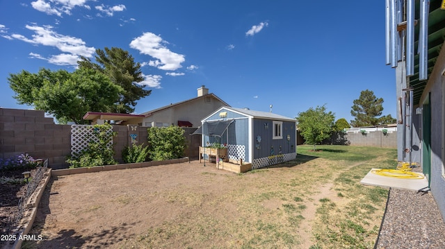 view of yard with an outbuilding, a fenced backyard, and a vegetable garden