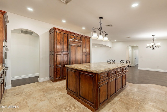 kitchen featuring decorative light fixtures, a center island, light stone countertops, and oven