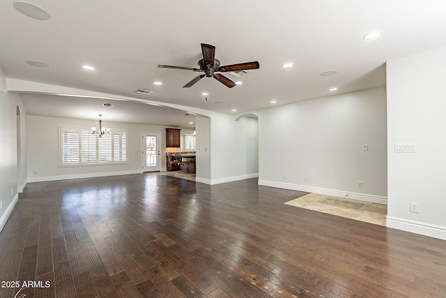 unfurnished living room with ceiling fan with notable chandelier and dark hardwood / wood-style flooring