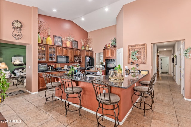 kitchen with sink, a kitchen breakfast bar, high vaulted ceiling, black appliances, and light tile patterned floors