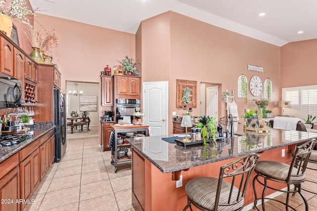 kitchen featuring a spacious island, a notable chandelier, a kitchen breakfast bar, and black appliances