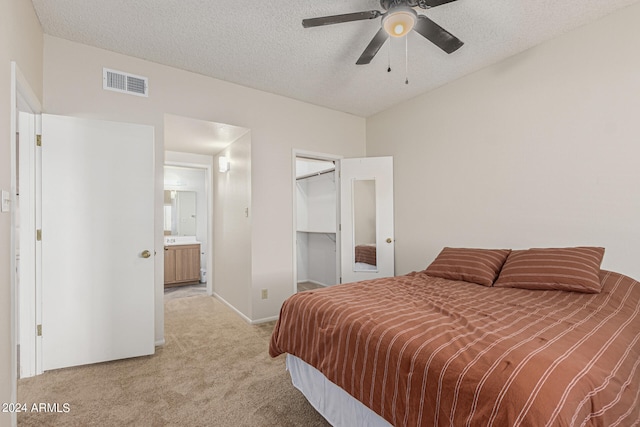 carpeted bedroom featuring a spacious closet, connected bathroom, and a textured ceiling