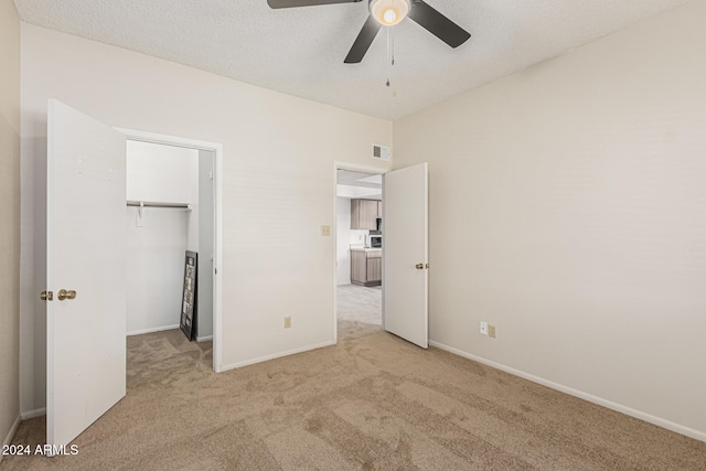 unfurnished bedroom with light carpet, a textured ceiling, and ceiling fan