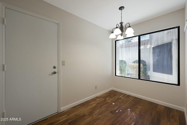 unfurnished dining area featuring dark wood-type flooring and an inviting chandelier