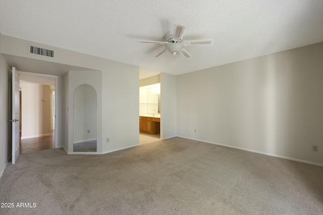 carpeted empty room with ceiling fan and a textured ceiling