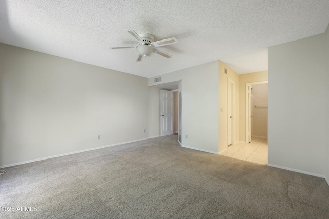 unfurnished room featuring a textured ceiling, ceiling fan, and light carpet