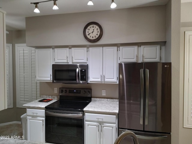 kitchen featuring rail lighting, stainless steel appliances, tile patterned flooring, and white cabinets