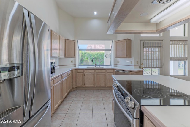 kitchen featuring appliances with stainless steel finishes, light tile patterned floors, light brown cabinetry, and sink