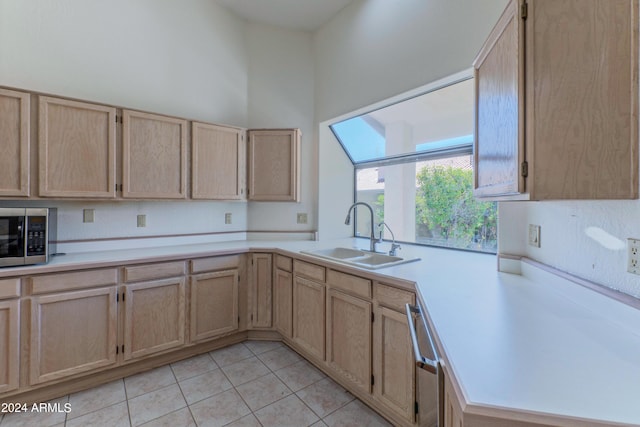 kitchen with sink, stainless steel appliances, a towering ceiling, light brown cabinetry, and light tile patterned floors