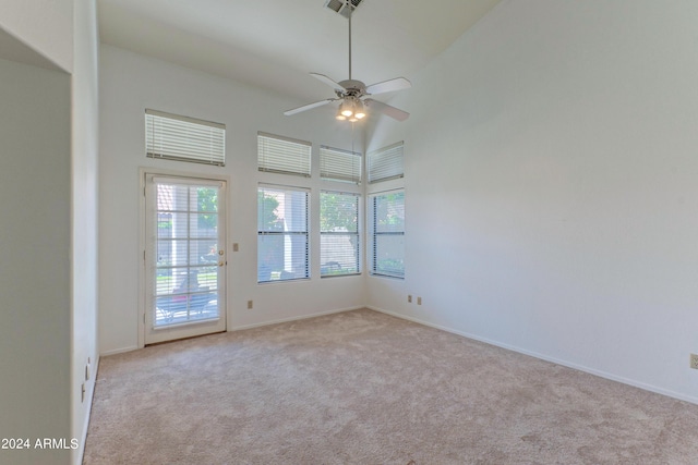 empty room featuring ceiling fan, high vaulted ceiling, and light colored carpet