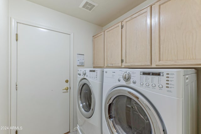 washroom with washer and clothes dryer and cabinets