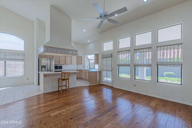 kitchen with appliances with stainless steel finishes, light wood-type flooring, light brown cabinetry, custom exhaust hood, and a breakfast bar area