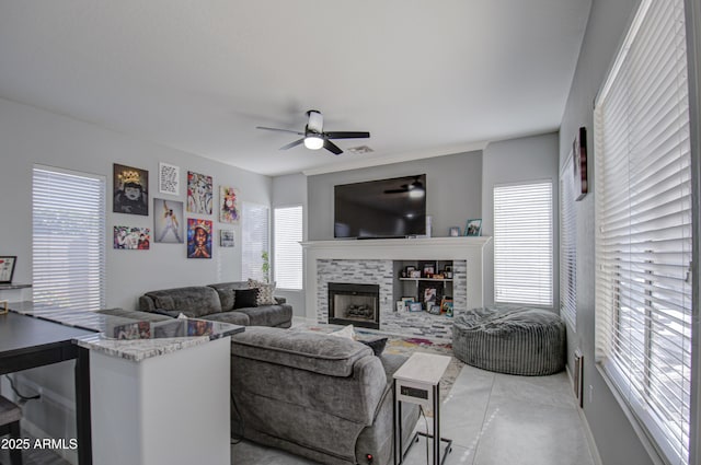 living room with ceiling fan and a tiled fireplace