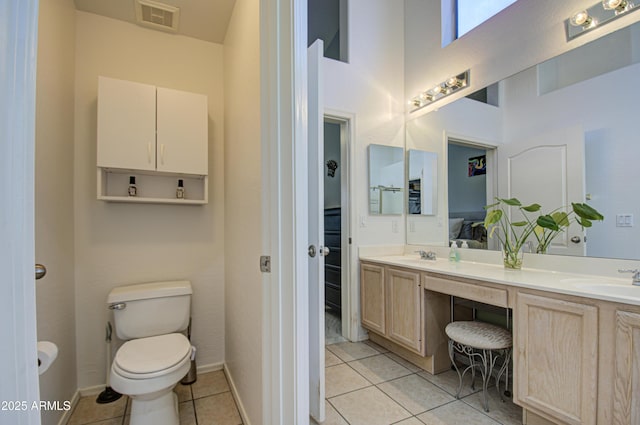 bathroom featuring tile patterned flooring, vanity, a towering ceiling, and toilet