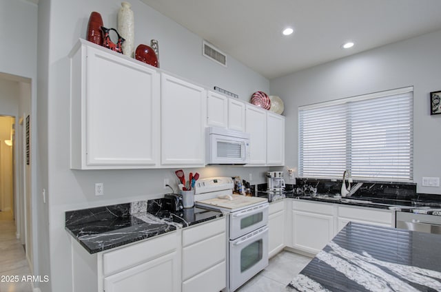 kitchen featuring sink, dark stone countertops, white cabinets, and white appliances