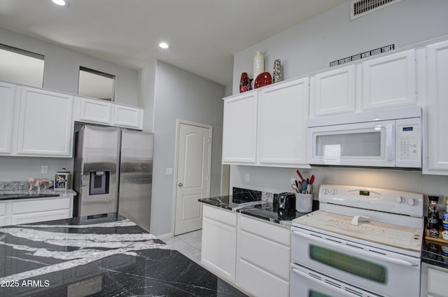 kitchen featuring white cabinetry, white appliances, dark stone counters, and light tile patterned floors