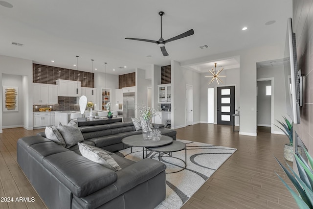 living room with hardwood / wood-style flooring and ceiling fan with notable chandelier