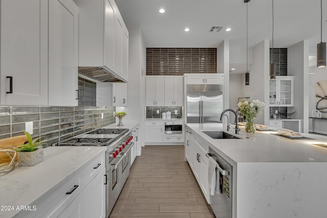 kitchen featuring white cabinets, premium appliances, and hanging light fixtures