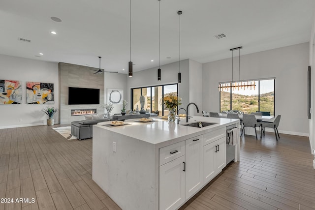 kitchen with white cabinetry, a kitchen island with sink, pendant lighting, and a healthy amount of sunlight