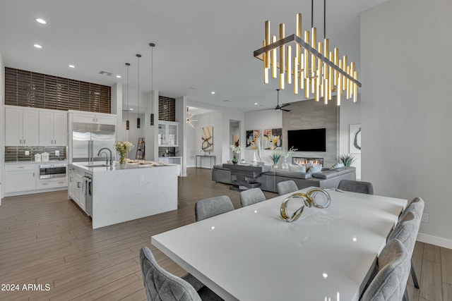 dining area featuring wood-type flooring, ceiling fan with notable chandelier, and sink