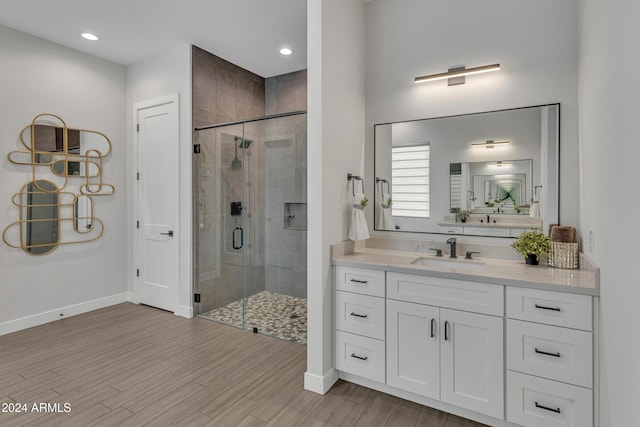 bathroom featuring hardwood / wood-style flooring, vanity, and a shower with door