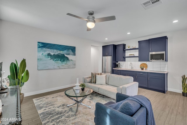 living room featuring light hardwood / wood-style flooring, ceiling fan, and sink