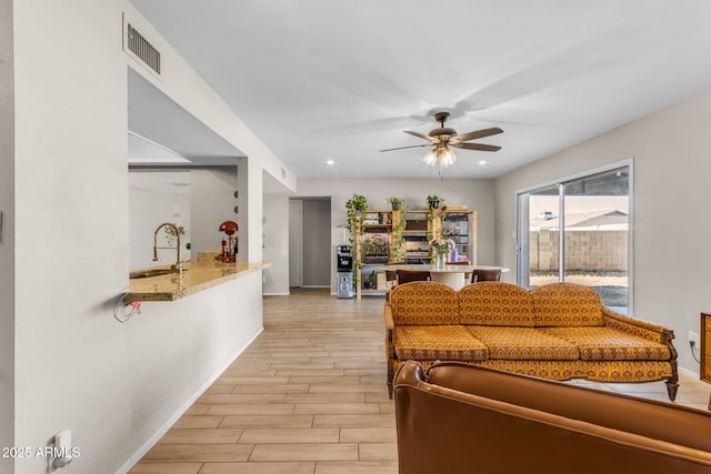 living room featuring ceiling fan and sink