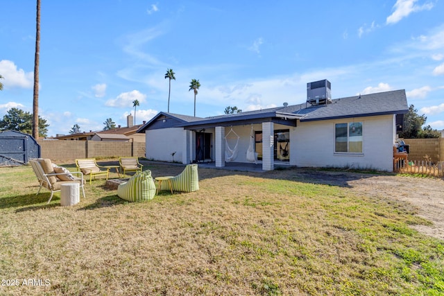 rear view of property featuring central air condition unit, a yard, and a shed