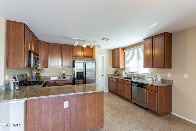 kitchen featuring light stone countertops, appliances with stainless steel finishes, kitchen peninsula, and rail lighting