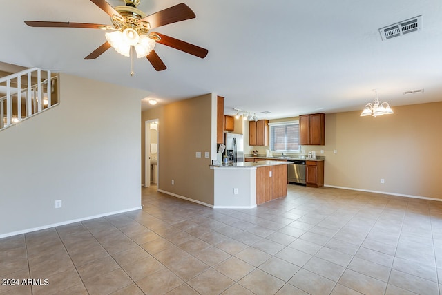 kitchen with appliances with stainless steel finishes, kitchen peninsula, light tile patterned floors, and ceiling fan with notable chandelier