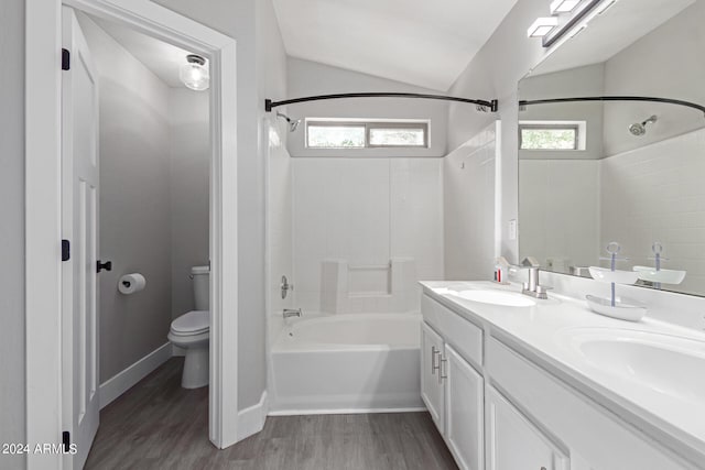 full bathroom featuring hardwood / wood-style floors, vanity, vaulted ceiling, tiled shower / bath combo, and toilet