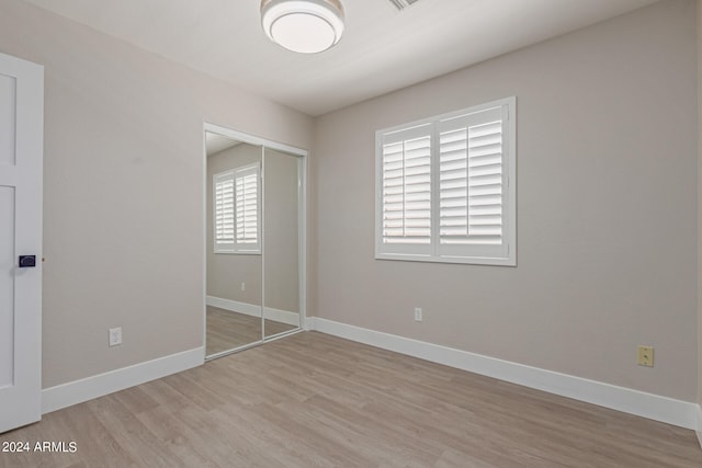 unfurnished bedroom featuring light hardwood / wood-style flooring and a closet