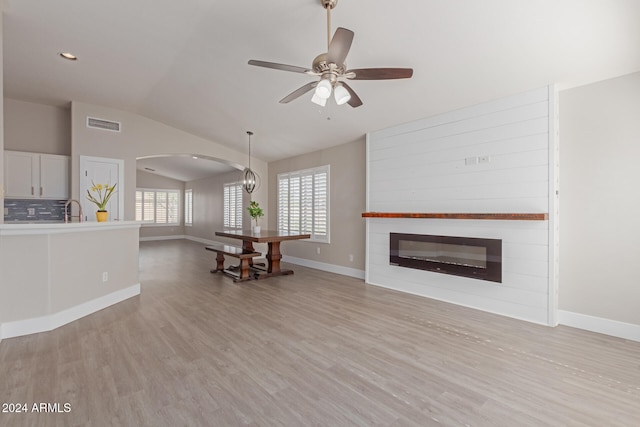 unfurnished living room with light hardwood / wood-style flooring, ceiling fan with notable chandelier, lofted ceiling, and sink