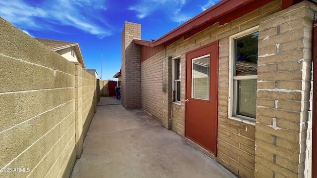 view of home's exterior featuring brick siding, fence, a chimney, and a patio