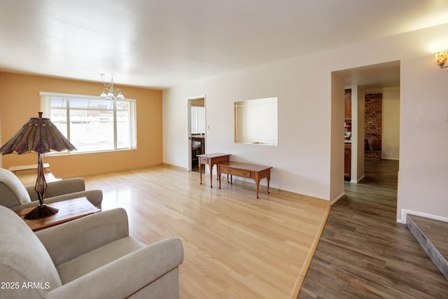 living room with baseboards, a chandelier, and wood finished floors