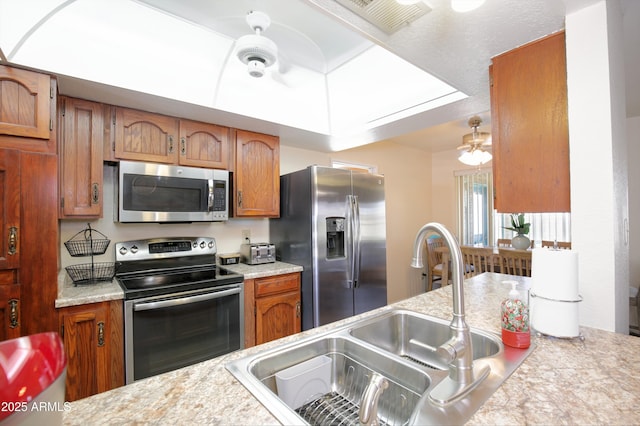 kitchen with brown cabinets, light countertops, visible vents, appliances with stainless steel finishes, and a sink