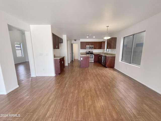 kitchen with a kitchen island, open floor plan, stainless steel appliances, and wood finished floors