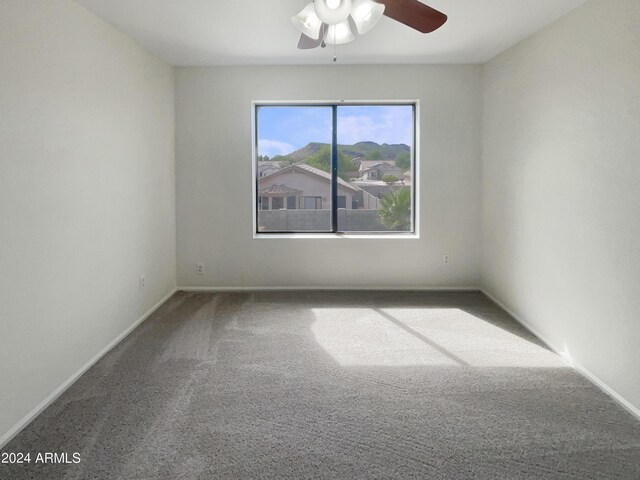 carpeted empty room featuring baseboards and ceiling fan