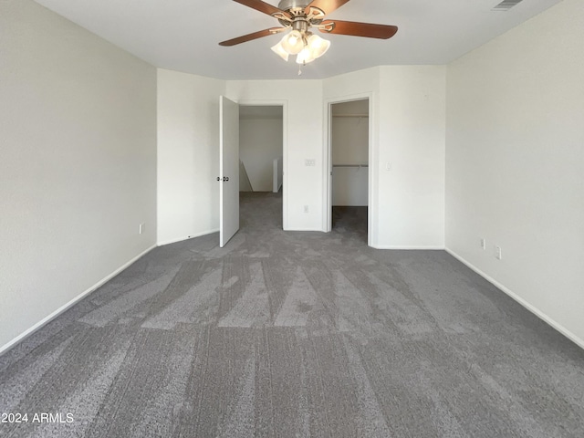 unfurnished bedroom with a spacious closet, visible vents, ceiling fan, baseboards, and carpet floors