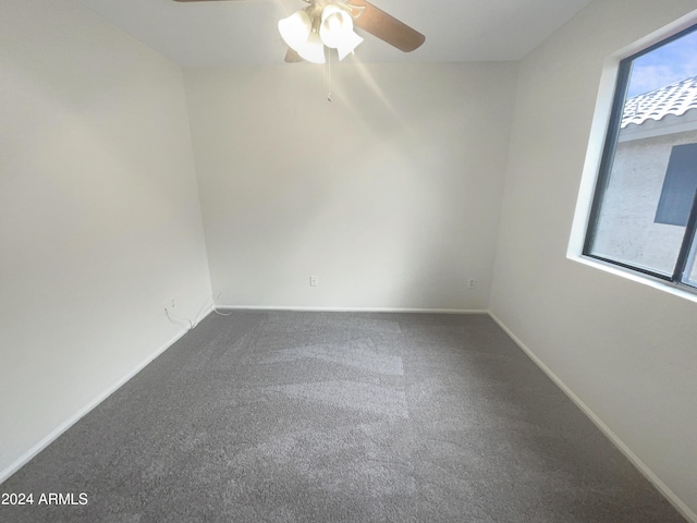 carpeted spare room featuring baseboards and a ceiling fan