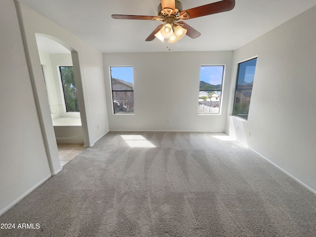 unfurnished room featuring plenty of natural light, ceiling fan, and light carpet