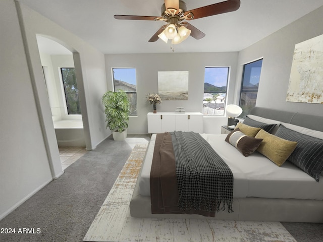 bedroom featuring ceiling fan, multiple windows, arched walkways, and ensuite bath