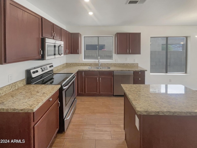 kitchen featuring recessed lighting, light stone countertops, stainless steel appliances, and a sink