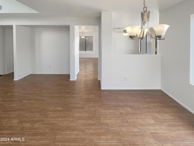 empty room featuring a notable chandelier, baseboards, and wood tiled floor